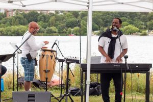 A keyboardist and bongo player sing together.