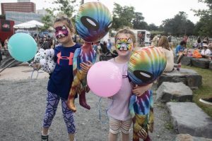 Two little girls show off their bright feline face paint and large prizes they have won