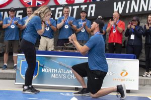 A male rower kneels and proposes to his girlfriend in the winners circle